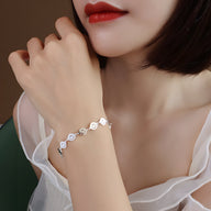 Bracelet en titane plaqué or à motifs smileys stylisés porté au poignet féminin avec peau claire et blouse blanche.