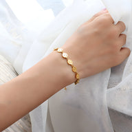 Bracelet fin en titane plaqué or avec motifs smileys ronds, porté au poignet féminin.