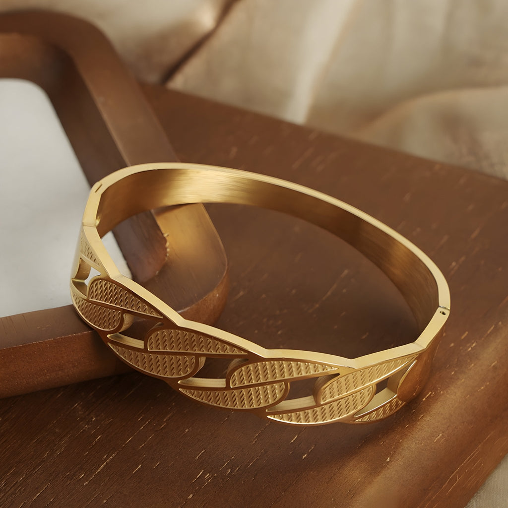 Bracelet jonc en titane plaqué or avec chaîne plate gravée, finition brillante et mate.