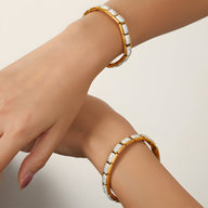 Bracelet rigide plaqué or en titane avec zircones carrées blanches, modèle Alice, porté aux poignets.