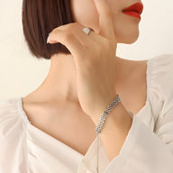 Bracelet montre en titane plaqué argent avec mailles tressées porté sur poignet féminin.