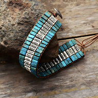 Bracelet multi-rangs bleu en turquoises carrées avec motifs floraux argentés et fermoir bouton en métal.