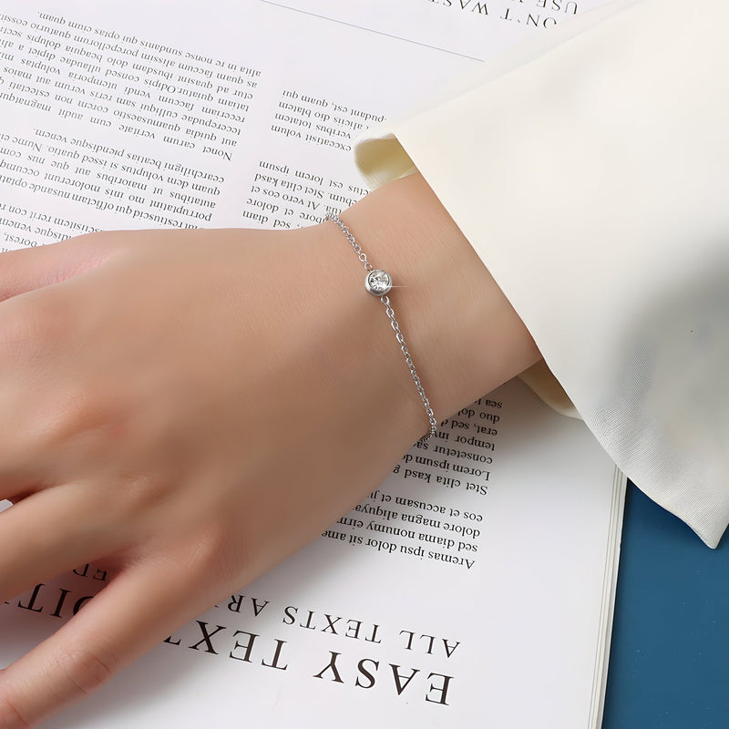 Bracelet fin en titane plaqué or avec un diamant incrusté sur chaîne délicate, porté au poignet.