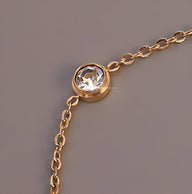 Bracelet fin en titane plaqué or avec diamant rond serti et chaîne délicate.