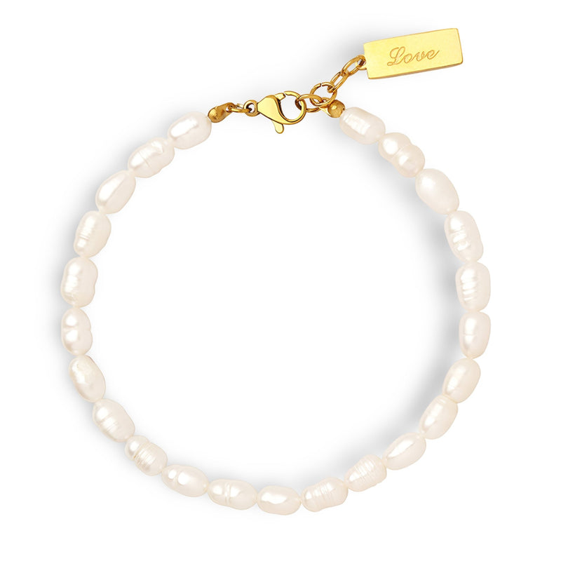 Bracelet délicat en perles blanches naturelles avec fermoir en titane doré et petit pendentif gravé.