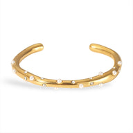 Bracelet jonc or avec perles blanches délicates réparties uniformément.