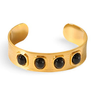 Bracelet jonc en métal doré avec quatre pierres naturelles noires ovales encastrées.