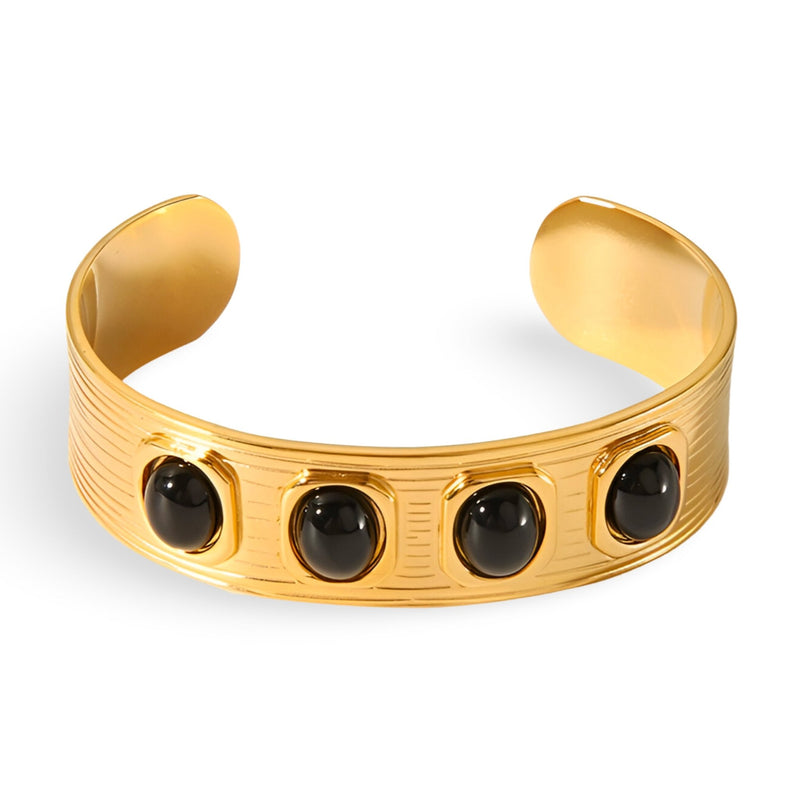 Bracelet jonc en métal doré avec quatre pierres naturelles noires ovales encastrées.