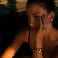 Bracelet jonc doré avec pierres noires naturelles porté au poignet femme élégante.