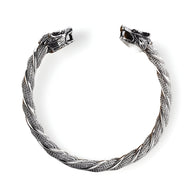 Bracelet jonc argenté en acier inoxydable avec double têtes de loup sculptées et motif tressé.