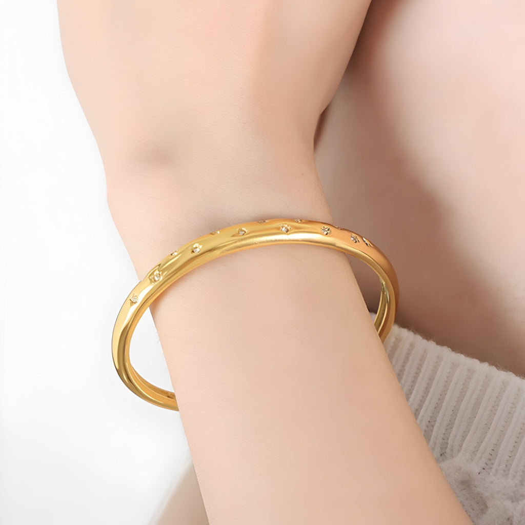 Bracelet jonc fin en titane plaqué or 18 carats avec zircons scintillants sur peau féminine.