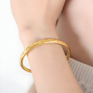 Bracelet jonc fin en titane plaqué or 18 carats avec zircons scintillants sur peau féminine.