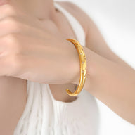 Bracelet jonc en titane plaqué or 18 carats avec zircons scintillants, modèle Gabriella, porté au poignet.