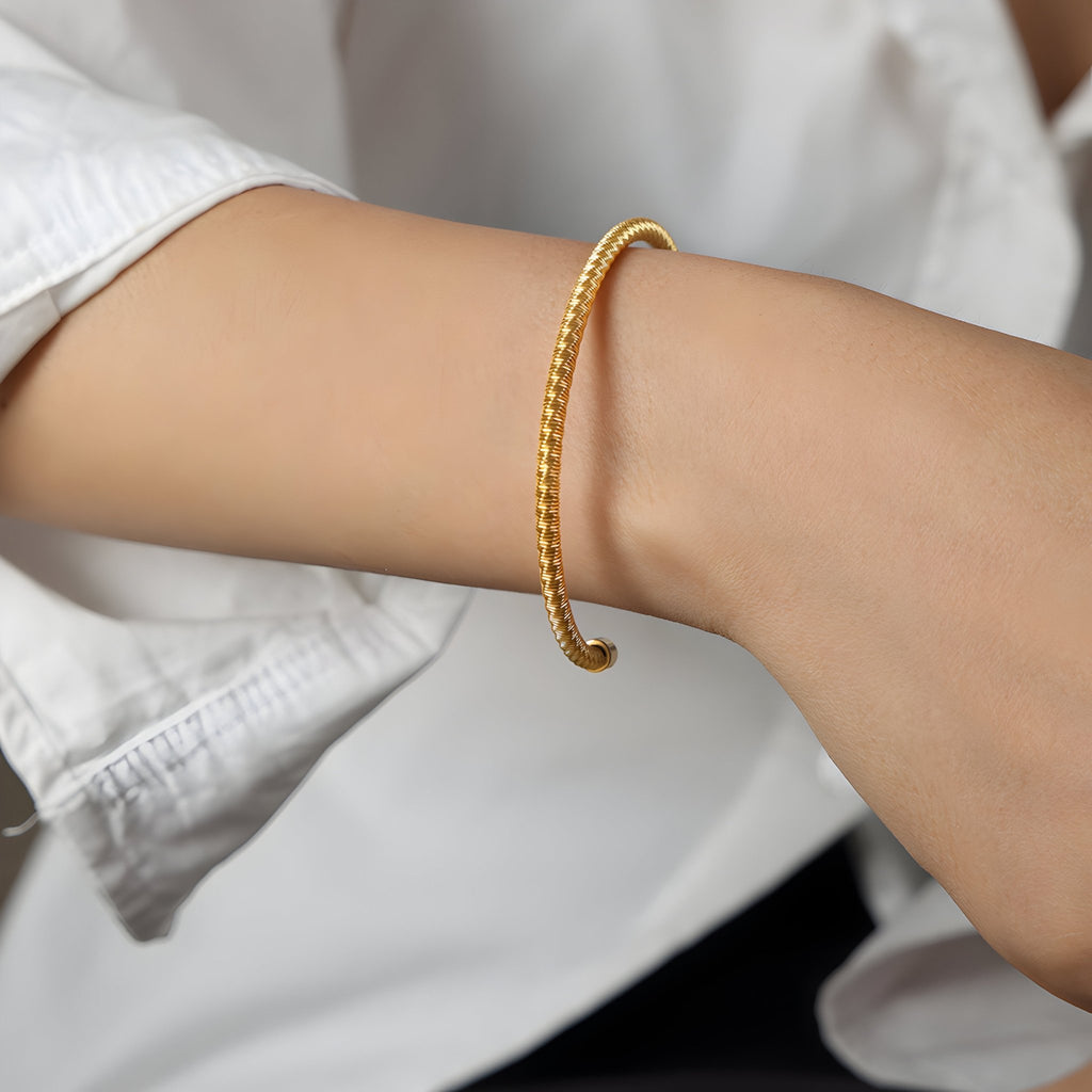 Bracelet jonc fin en titane plaqué or avec motif torsadé, modèle Iris.