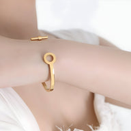 Bracelet jonc en titane plaqué or, finition lisse avec extrémités rondes ouvertes.