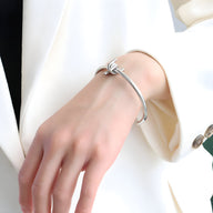 Bracelet jonc fin en titane plaqué argent avec nœud élégant porté sur poignet féminin.