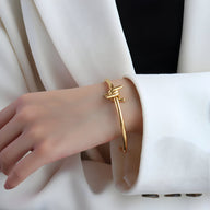 Bracelet jonc fin en titane plaqué or 18 carats avec nœud élégant porté sur poignet féminin.