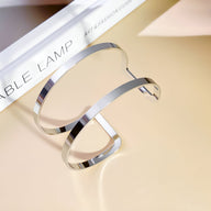 Bracelet manchette double rang en métal argenté lisse et brillant, style minimaliste élégant.