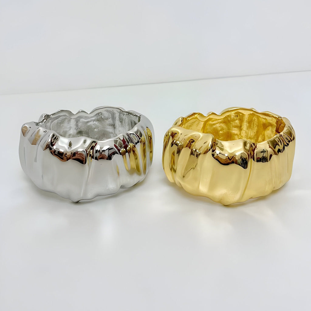 Bracelet manchette ondulé en métal doré et argenté avec finition brillante et texture gaufrée.