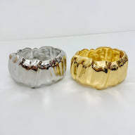 Bracelet manchette ondulé en métal doré et argenté avec finition brillante et texture gaufrée.