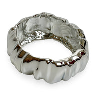 Bracelet manchette argenté à texture ondulée brillante et surface lisse sculptée.