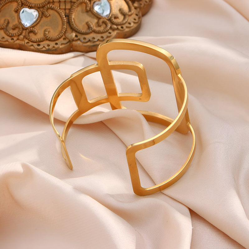 Bracelet manchette en métal doré avec design géométrique ouvert style contemporain.