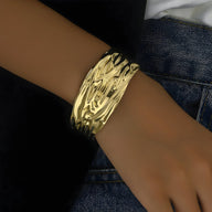 Bracelet manchette en or jaune avec surface texturée ondulée et finition brillante.