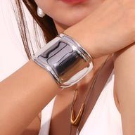 Bracelet manchette en acier inoxydable argenté, finition miroir brillante, design large et incurvé.