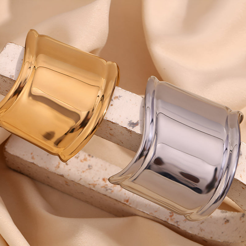 Bracelet manchette large en acier inoxydable or brillant et argenté lisse, design épuré et contemporain.