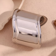 Bracelet manchette large en acier inoxydable argenté, finition brillante et design minimaliste incurvé.