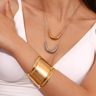 Bracelet manchette doré en acier inoxydable lisse et brillant, design large et incurvé.