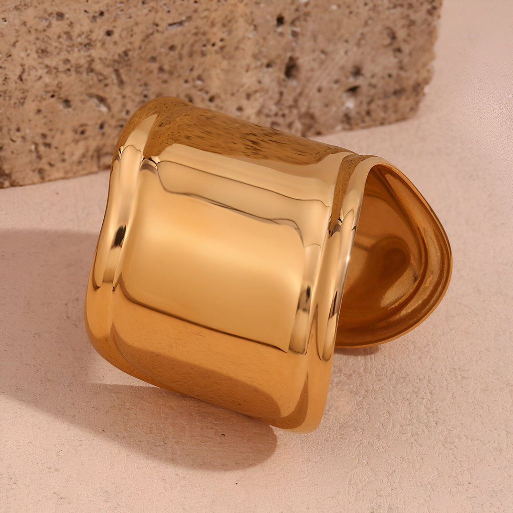 Bracelet manchette large en acier inoxydable doré, finition lisse brillante.