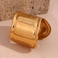 Bracelet manchette large en acier inoxydable doré, finition lisse brillante.