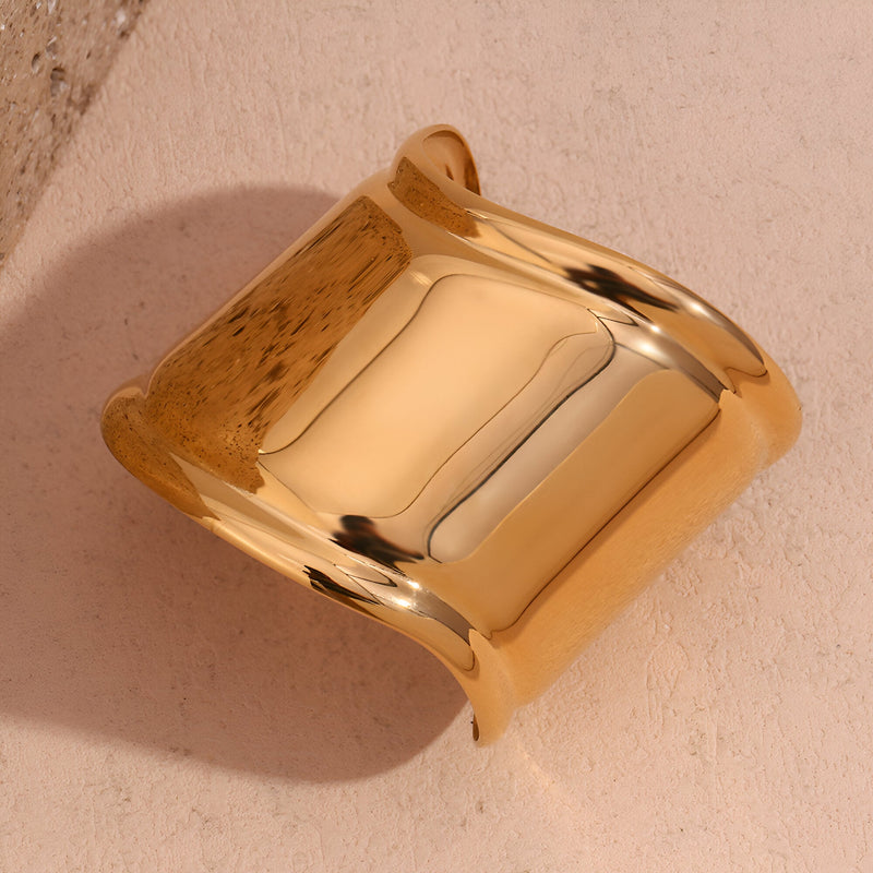 Bracelet manchette large en acier inoxydable doré, finition lisse et brillante.