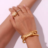 Bracelet manchette doré en forme de buste de femme, finition lisse et sculpturale.