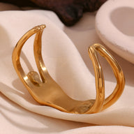 Bracelet manchette doré en forme de buste féminin stylisé, finition lisse et brillante.