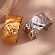 Bracelet manchette ondulé en acier inoxydable, finition or brillant et argenté, design moderne et texturé.