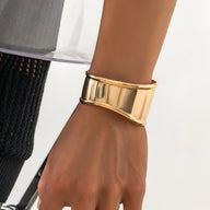 Bracelet manchette homme en métal doré poli au design large et incurvé.