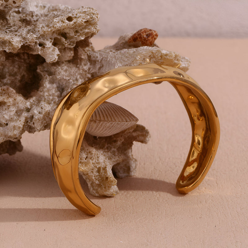 Bracelet manchette en acier inoxydable doré avec surface lisse et forme incurvée élégante.