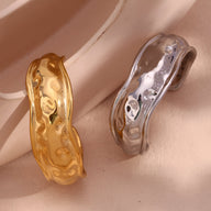 Bracelet manchette sculptural en acier inoxydable, finition or brillant et argentée, design ondulé texturé.