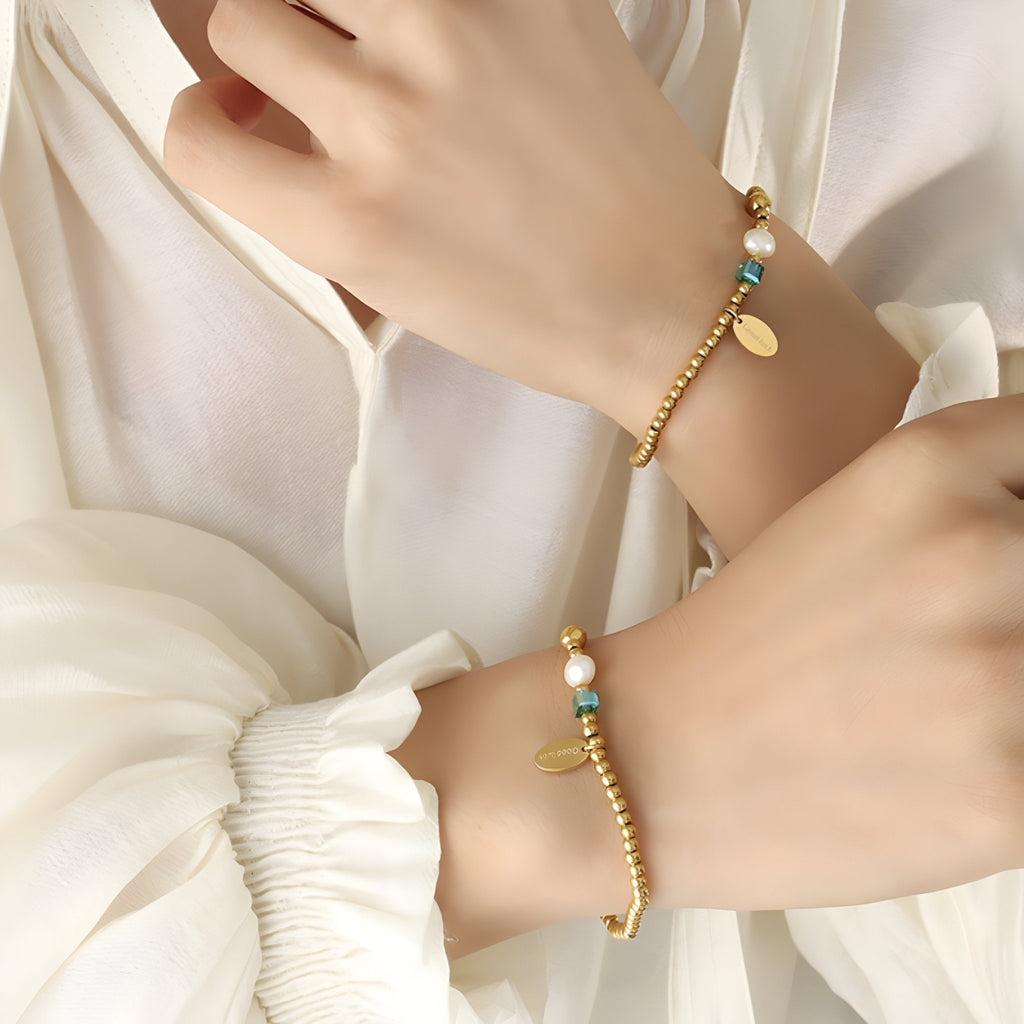 Bracelet en titane doré à fines perles, perle d'eau douce et cristal avec breloques rondes.