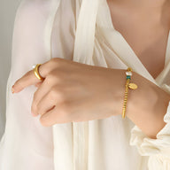 Bracelet perlé doré en titane avec perle d'eau douce et cristal sur poignet féminin.