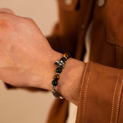 Bracelet homme perles marron oeil de tigre et tête de loup argentée sur poignet.