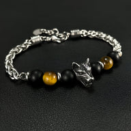 Bracelet homme chaîne argentée avec perles noires, œil de tigre marron et tête de loup en métal.