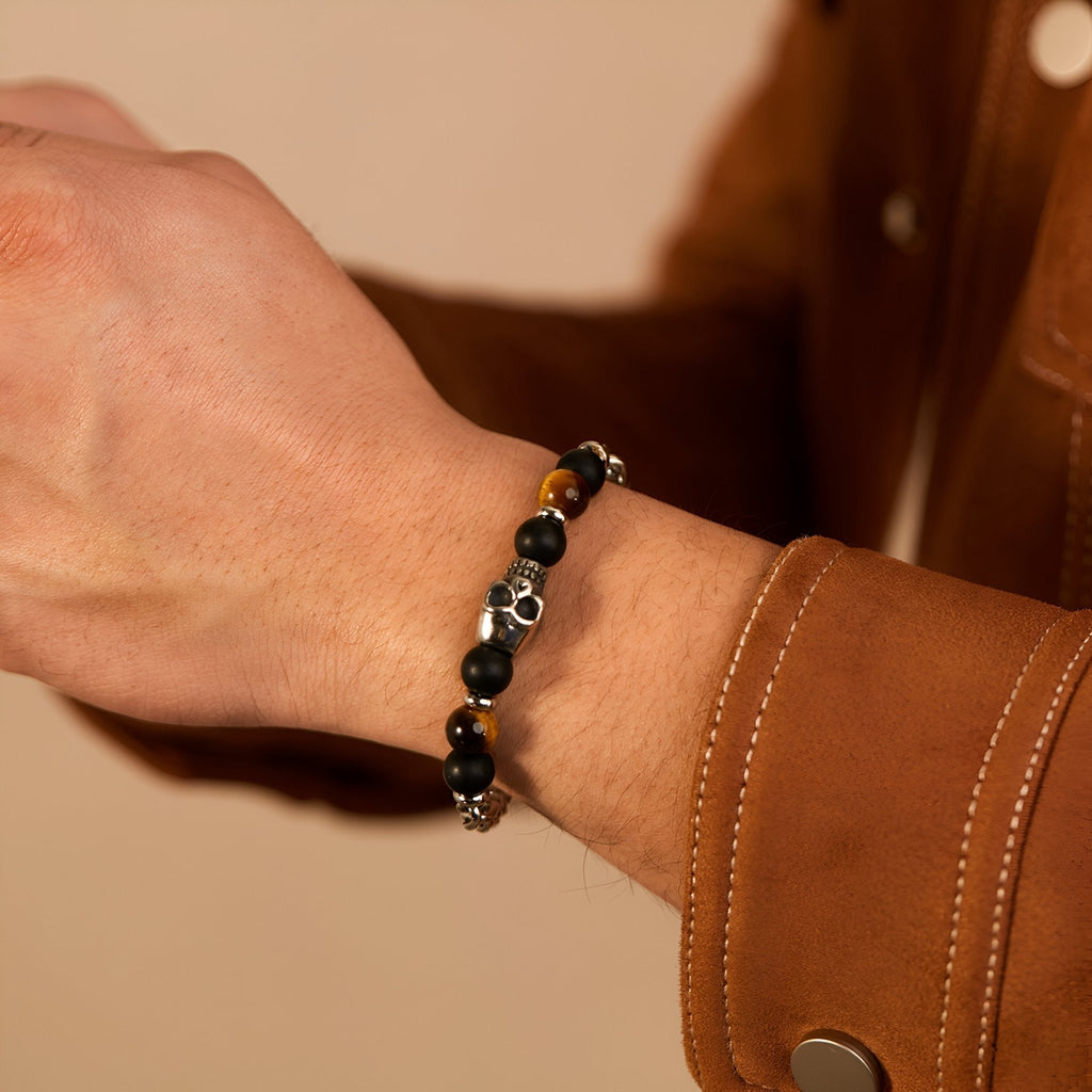 Bracelet pour homme en perles noir et œil de tigre avec tête de mort argentée, style rock.