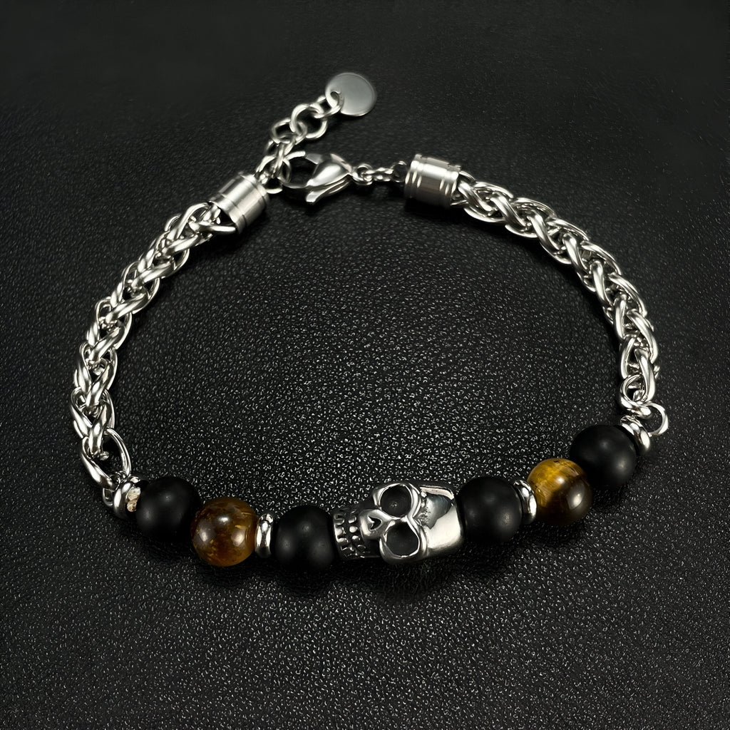 Bracelet homme en acier avec tête de mort argentée, perles noires mates et œil de tigre marron.