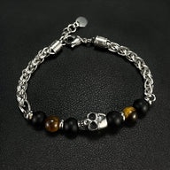 Bracelet homme en acier avec tête de mort argentée, perles noires mates et œil de tigre marron.