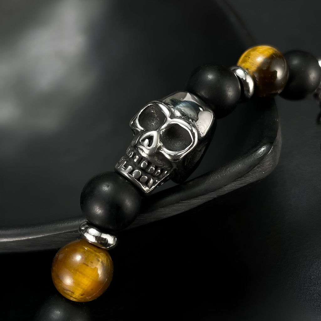 Bracelet homme en perles noires et œil de tigre marron avec tête de mort métal argenté.