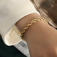 Bracelet torsadé en titane plaqué or 18 carats, finesse et éclat sur poignet féminin.