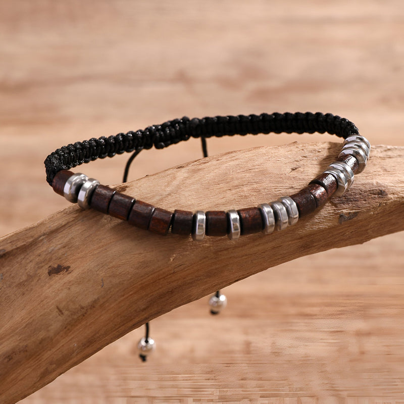 Bracelet homme en perles bois carré marron et noir avec éléments métalliques argentés sur cordelette noire tressée.